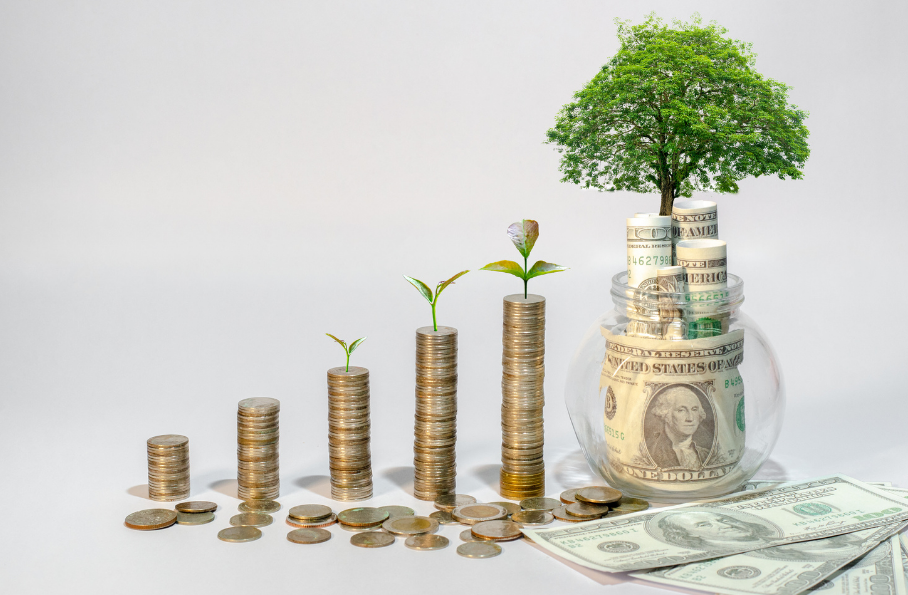 Fünf Geldmünzentürme stehen nebeneinander. Die Türme werden immer größer und schließlich wächst ein Baum aus dem Geldturm. Aus dem Münzenturm werden Geldscheine, aus denen ein Baum wächst. Dies symbolisiert, das stetige Geldwachstum, wenn man das richtige Finanzmindset hat und dem richtigen Umgang mit Geld erlernt.