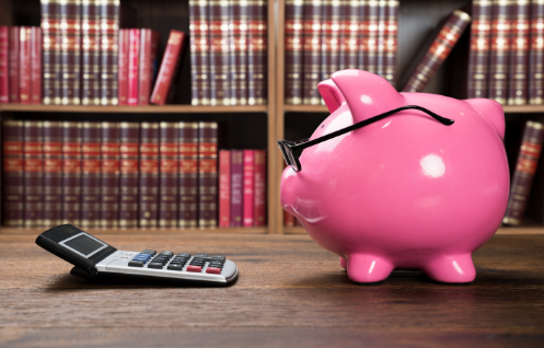 ein pinkes Sparschwein mit einer Brille auf der Nase, welches vor einem Taschenrechner und in der Bibliothek sitzt. Der Beitrag zeigt Steuer-Tipps für Eltern in Bezug auf Freibeträge und Steuer-Tricks